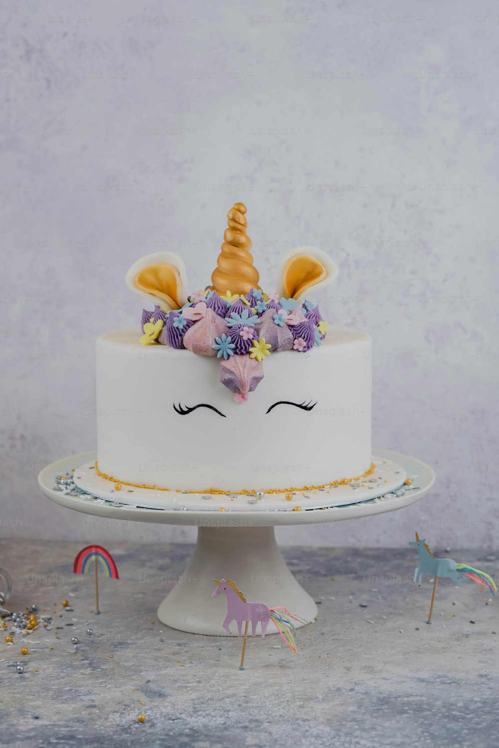 un gâteau blanc avec un visage de licorne sur le dessus