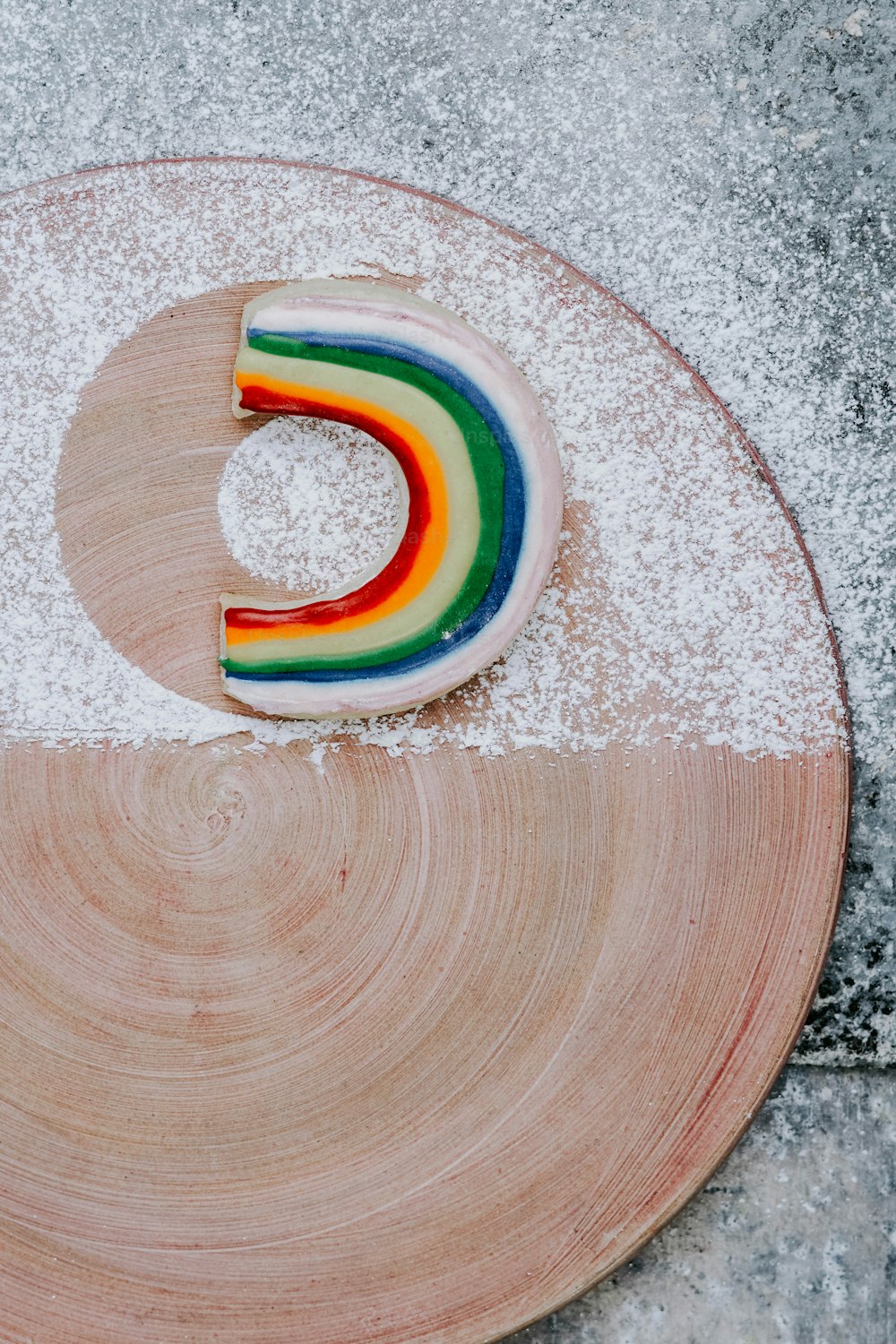 um bolo arco-íris sentado em cima de um prato de madeira