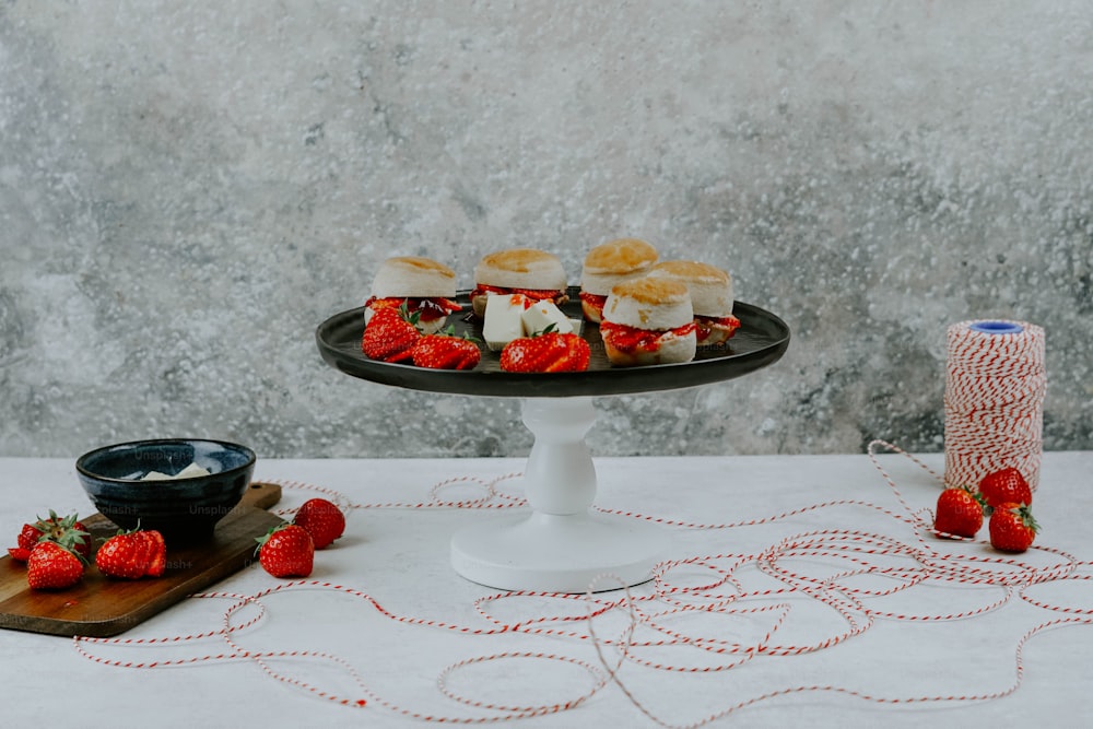 uma mesa coberta com um prato de comida e uma tigela de morangos