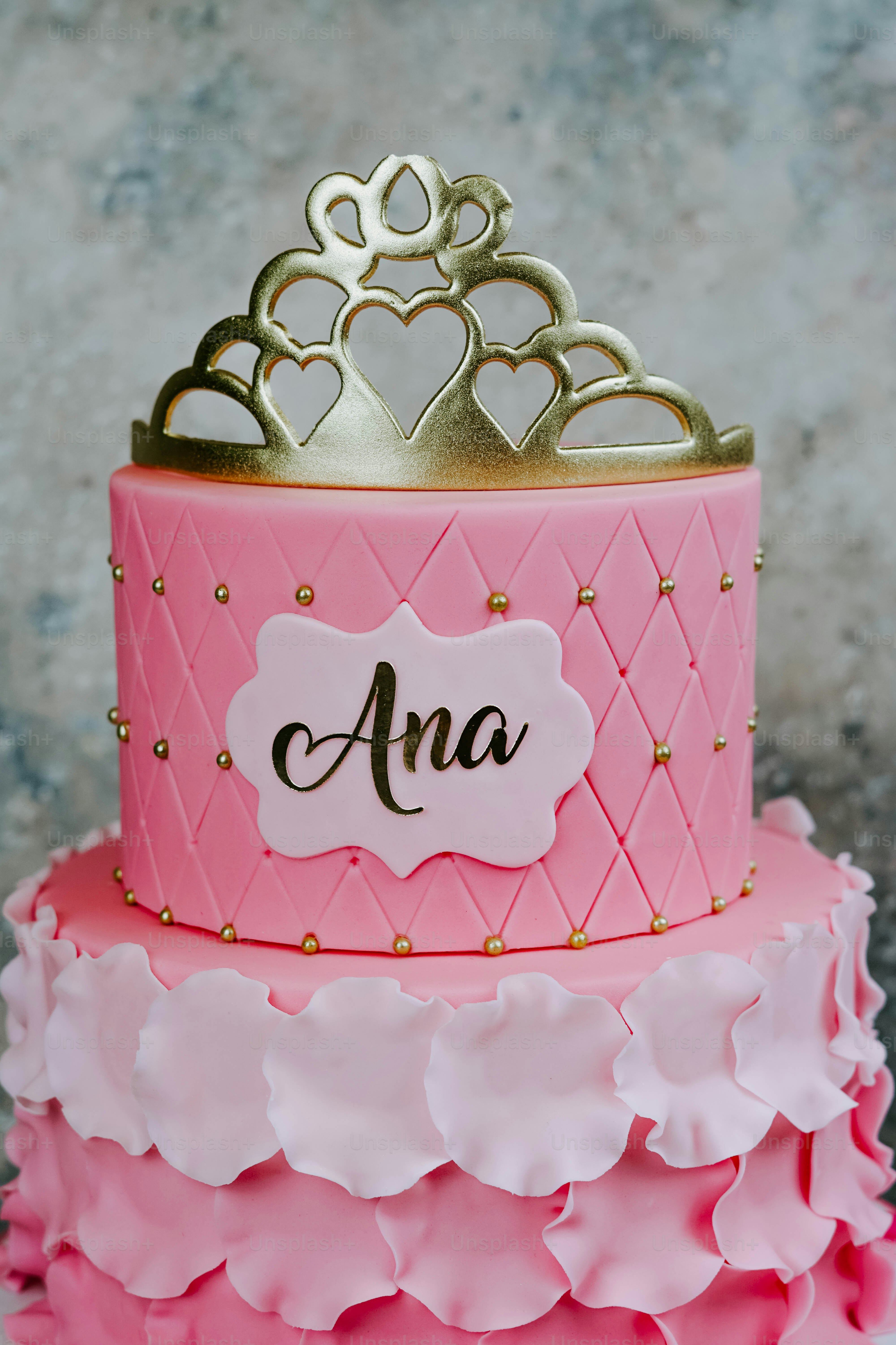 ein rosa-goldener Kuchen mit einer Tiara oben drauf