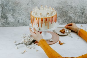 a woman decorating a cake with caramel drizzle