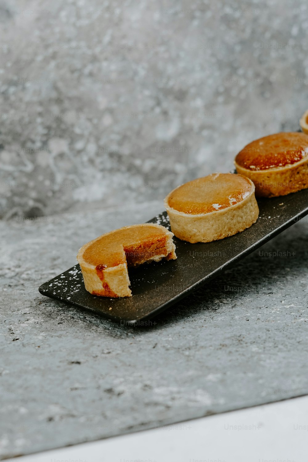 a black plate topped with mini pies on top of a table