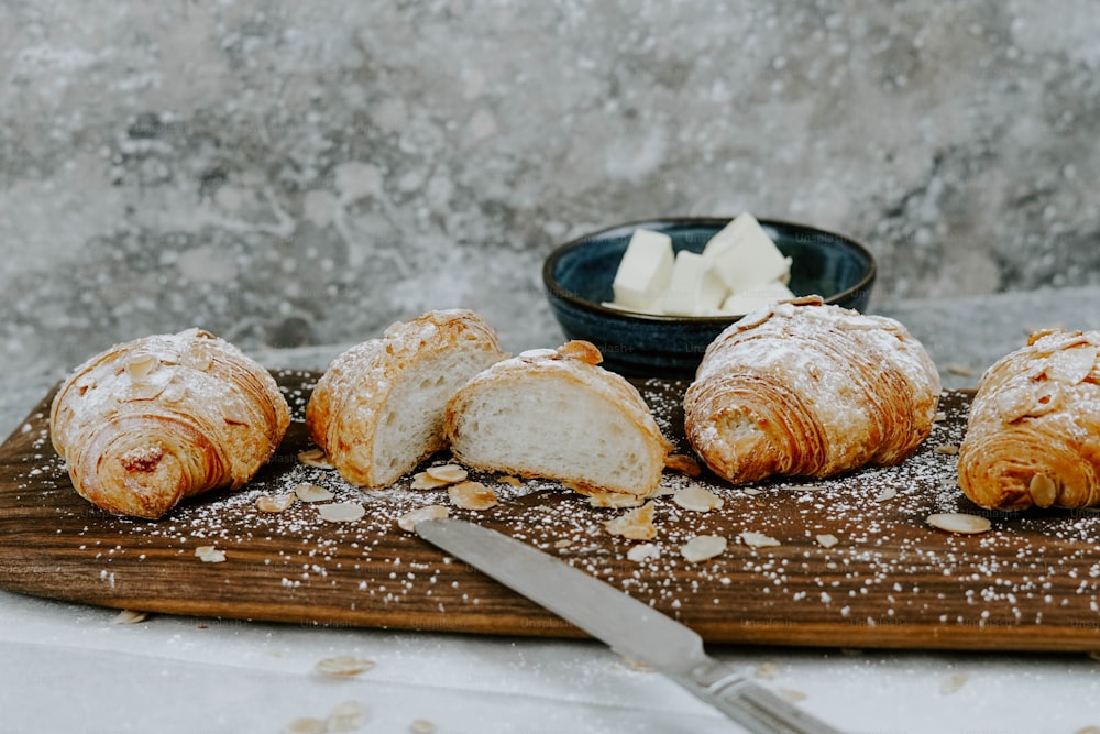 a wooden cutting board topped with croissants covered in powdered sugar