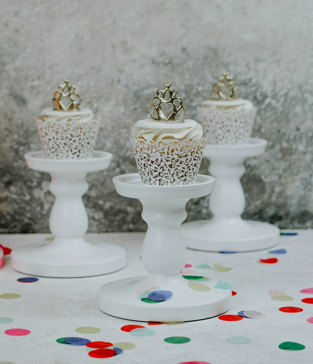 a table topped with three white cupcakes covered in frosting