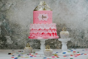 una torta di compleanno rosa e oro con cupcakes e confetti
