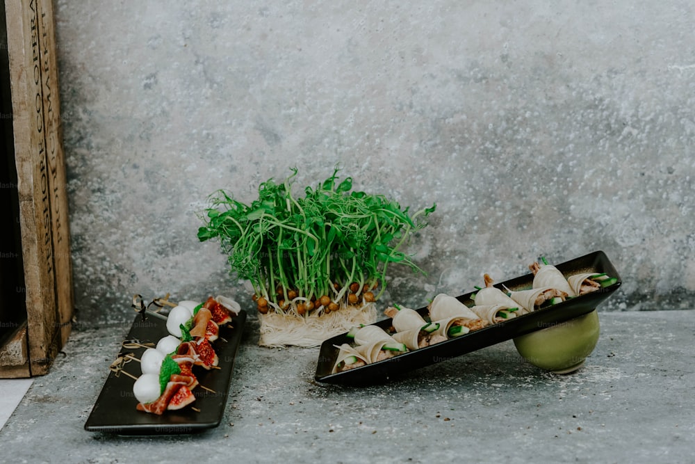 uma mesa coberta com bandejas de comida ao lado de um vaso de planta