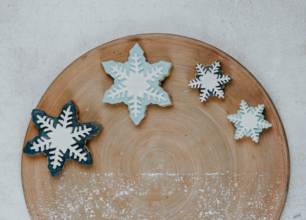 a wooden plate topped with snowflake cookies on top of a table
