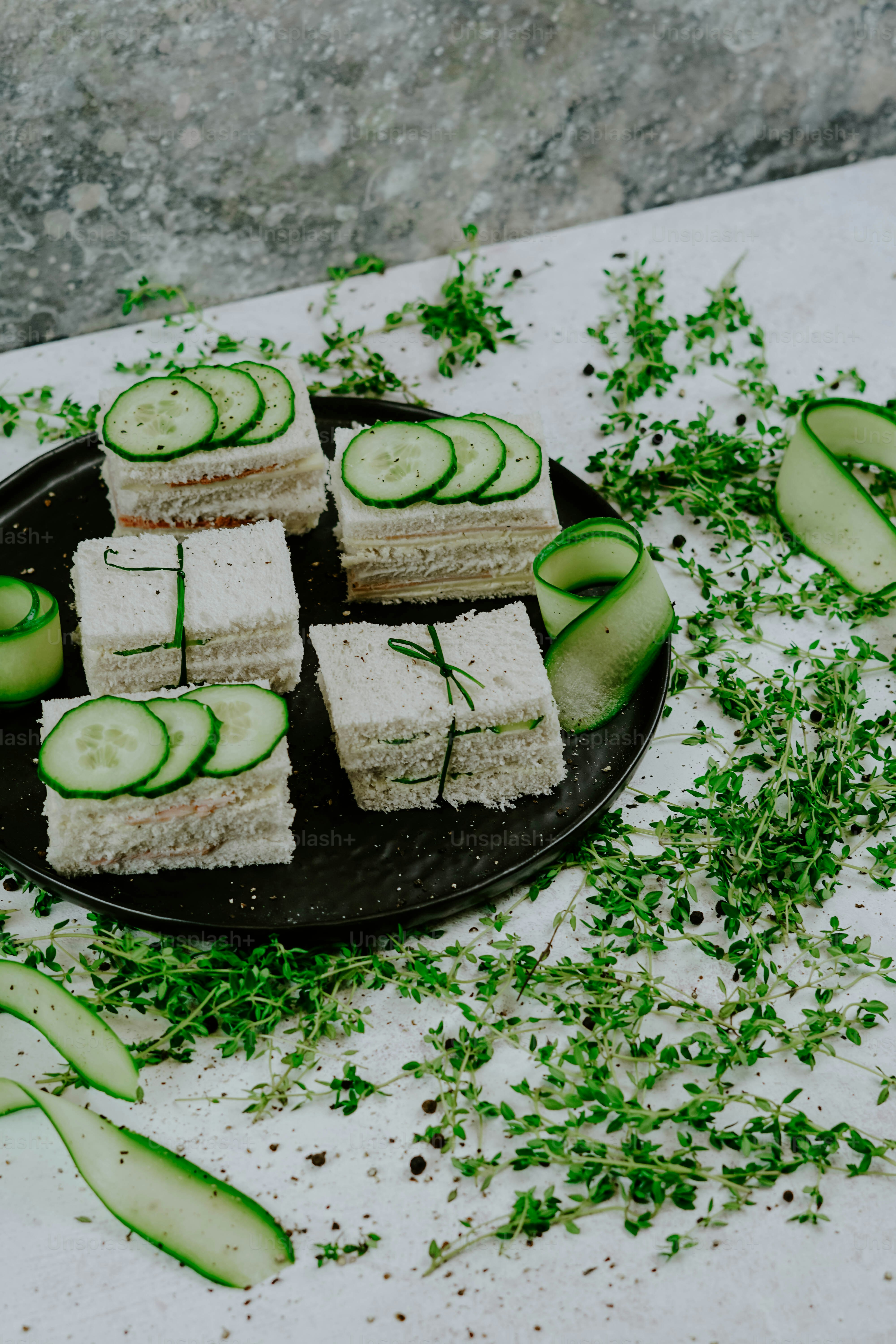 um prato de sanduíches de pepino em uma mesa