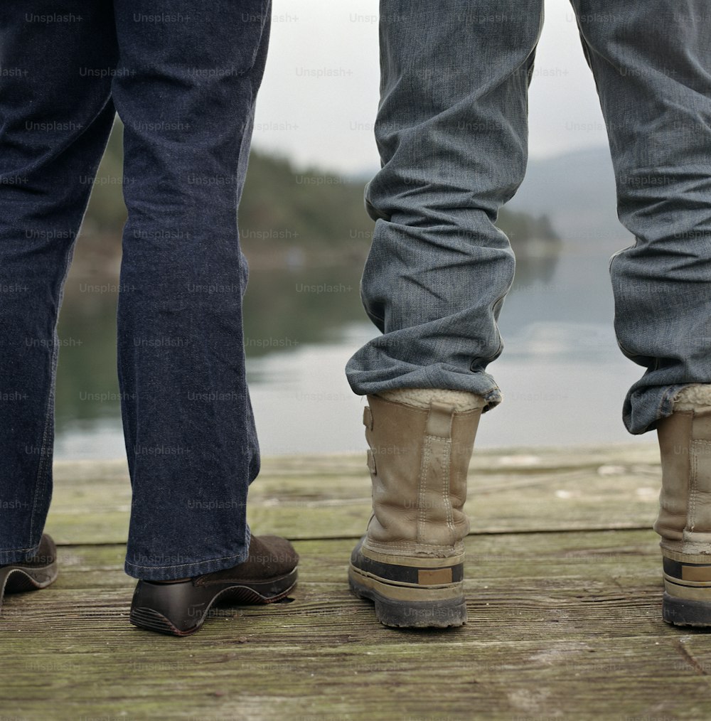 a couple of people standing on top of a wooden pier