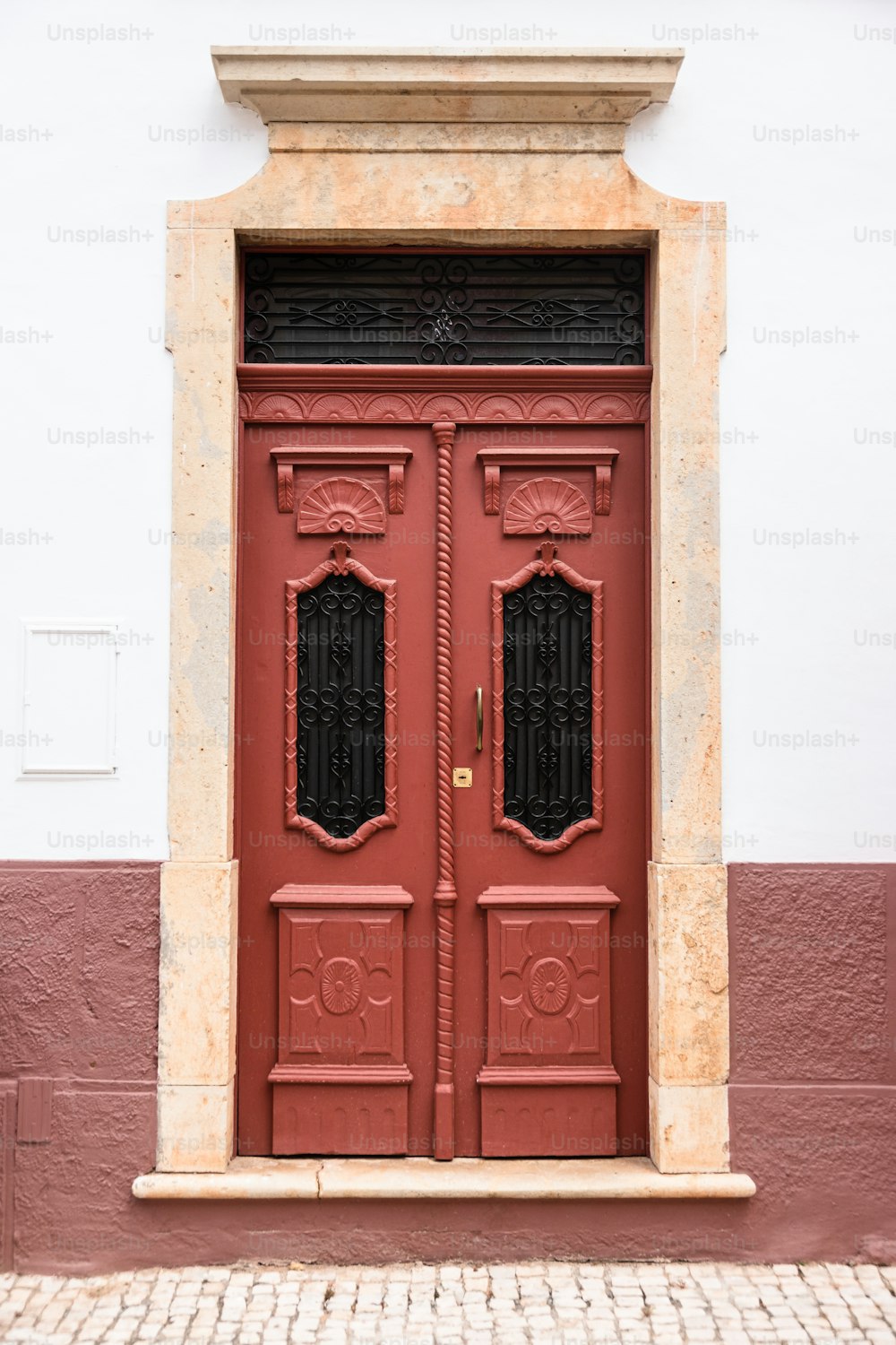 a red door with two windows on a white wall