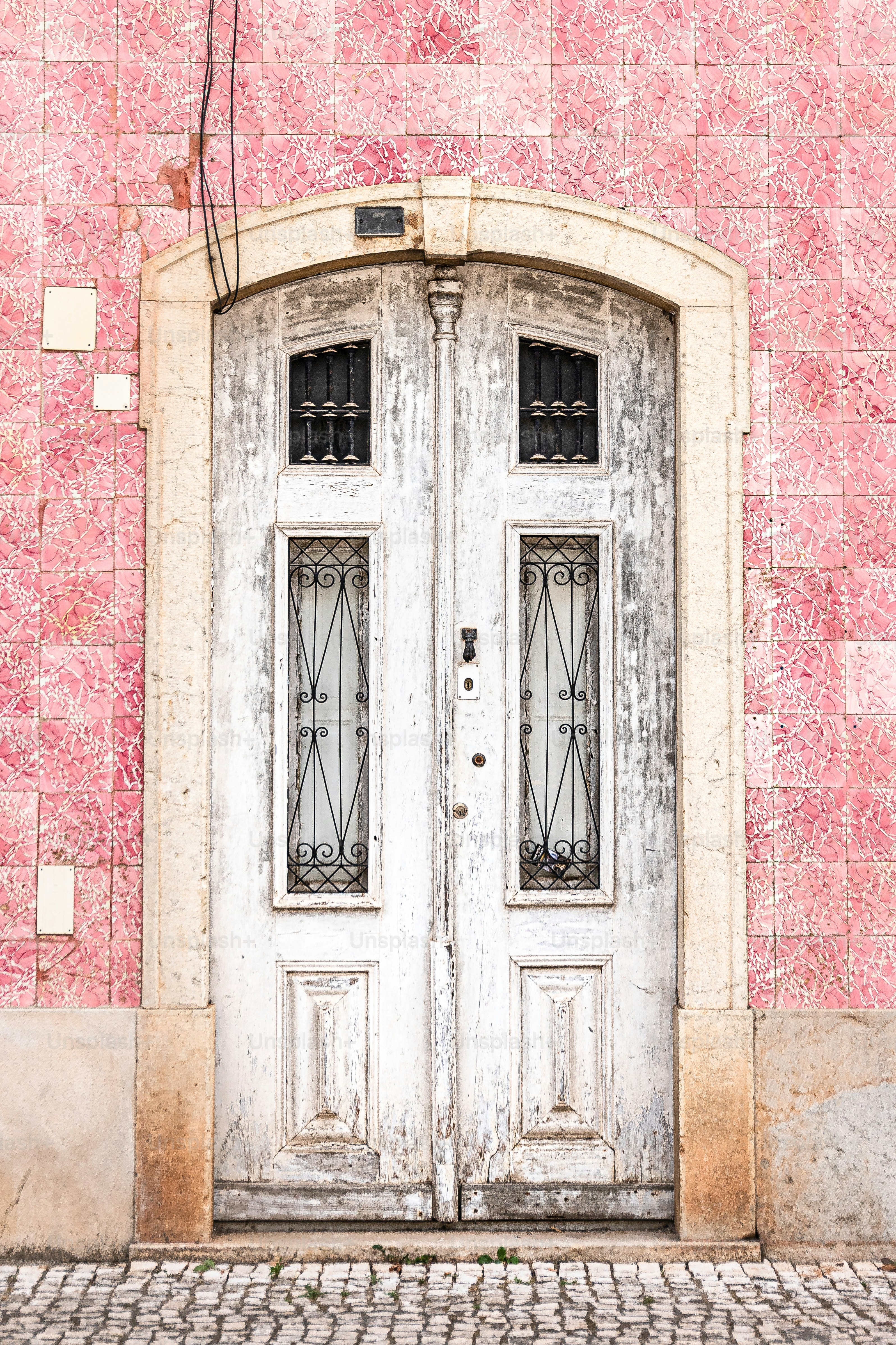 une double porte blanche assise à côté d’un mur de briques