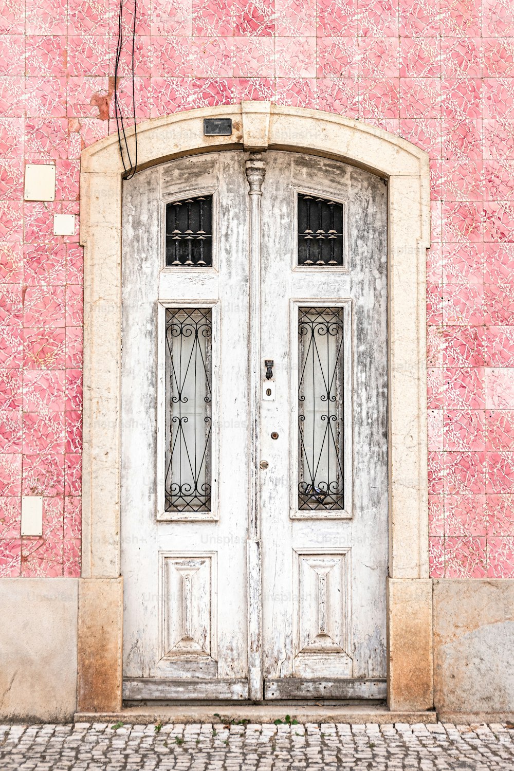 Una puerta doble blanca sentada junto a una pared de ladrillo
