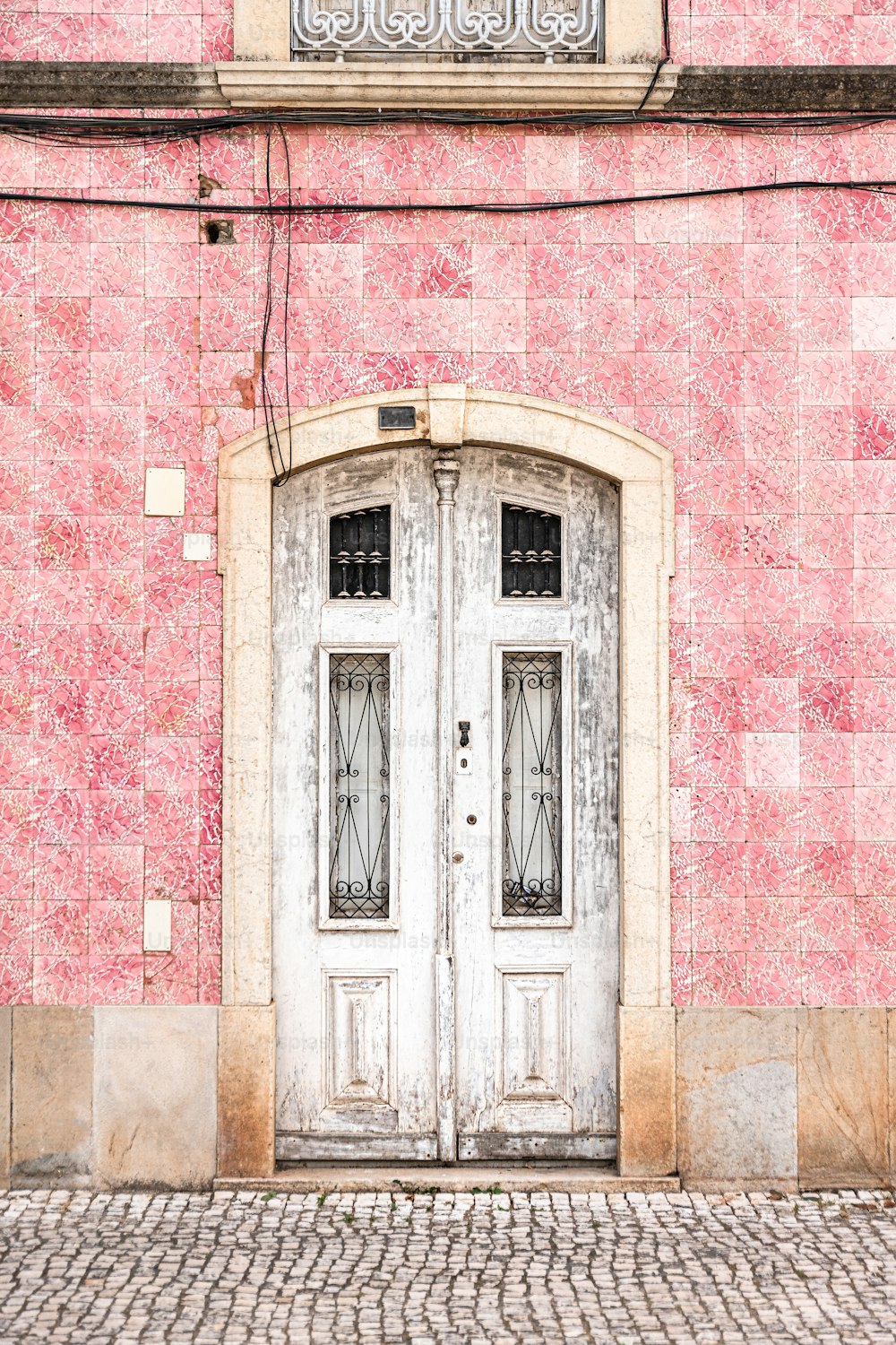 uma porta dupla branca em um edifício de tijolo rosa