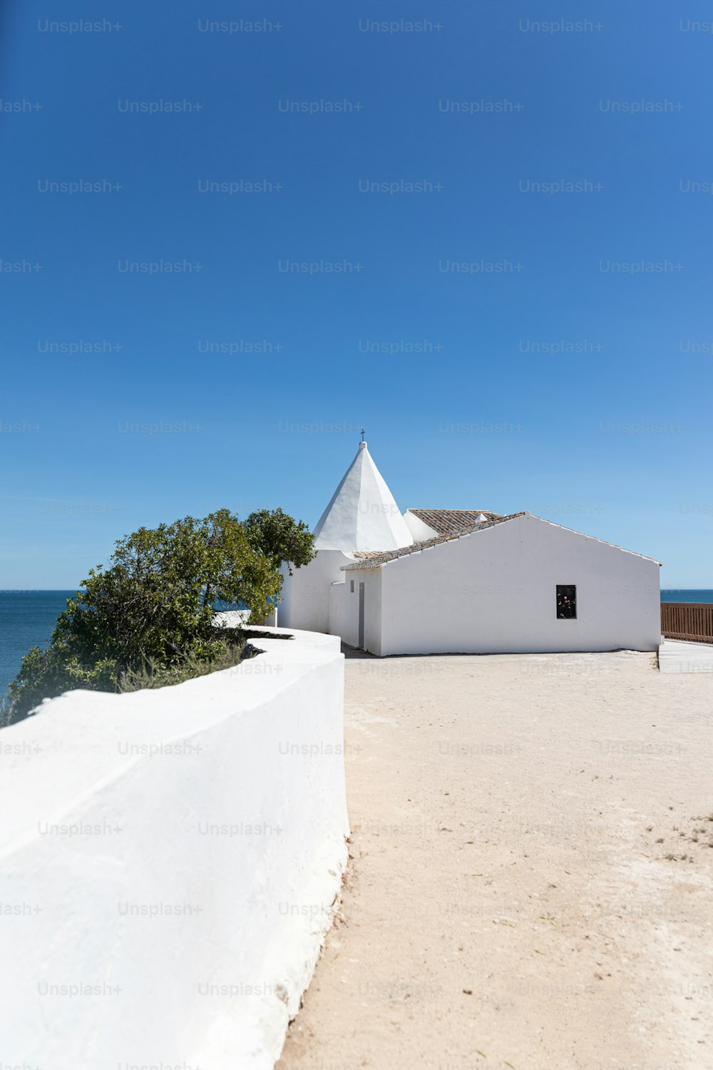 um edifício branco sentado no topo de uma praia de areia