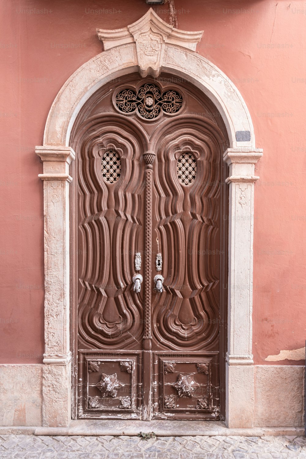 a large wooden door on a pink building