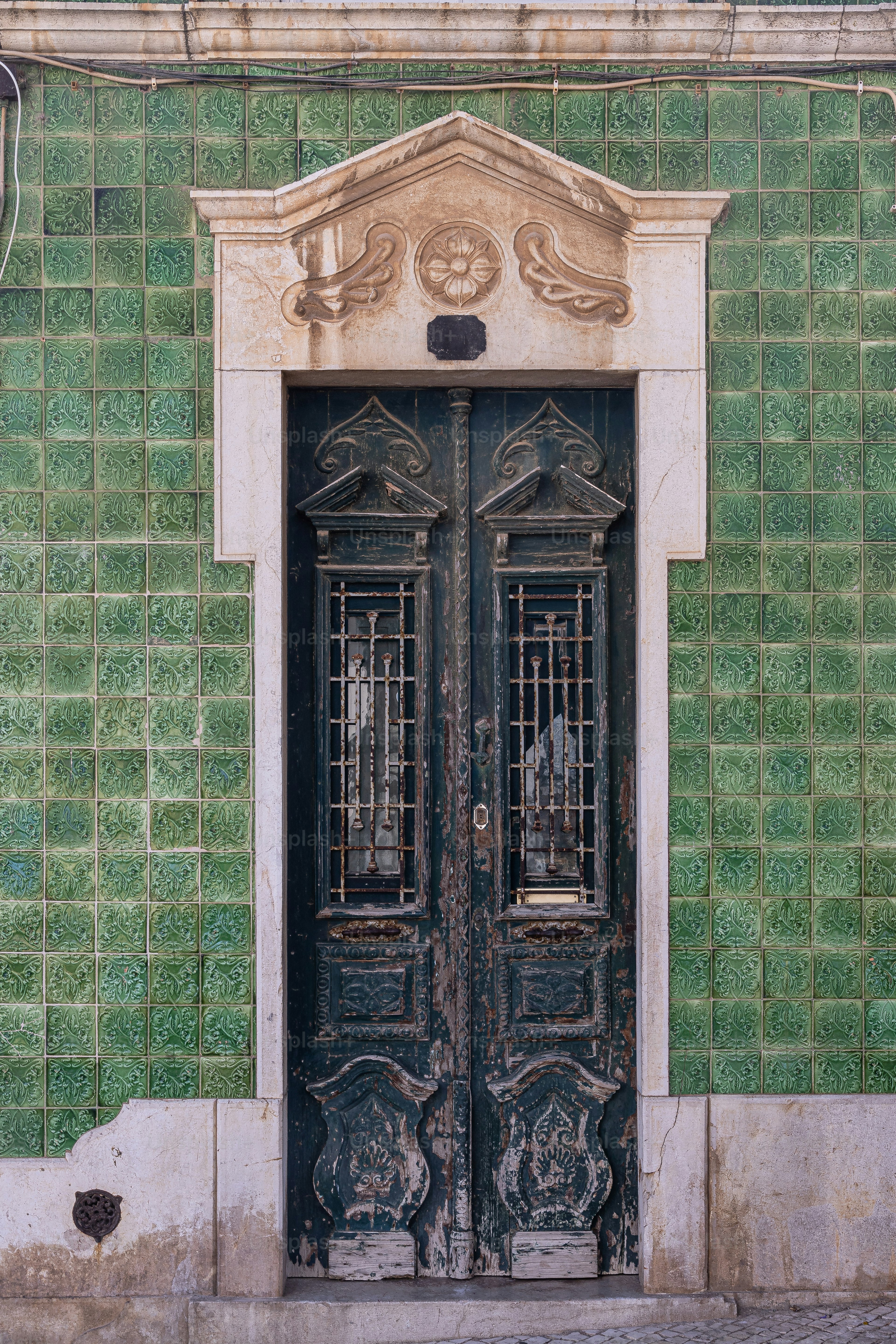 Un edificio de azulejos verdes con dos puertas negras