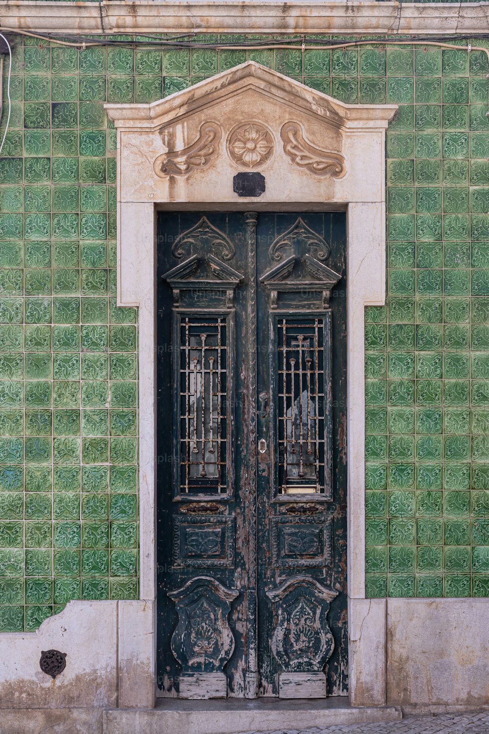 Un edificio de azulejos verdes con dos puertas negras