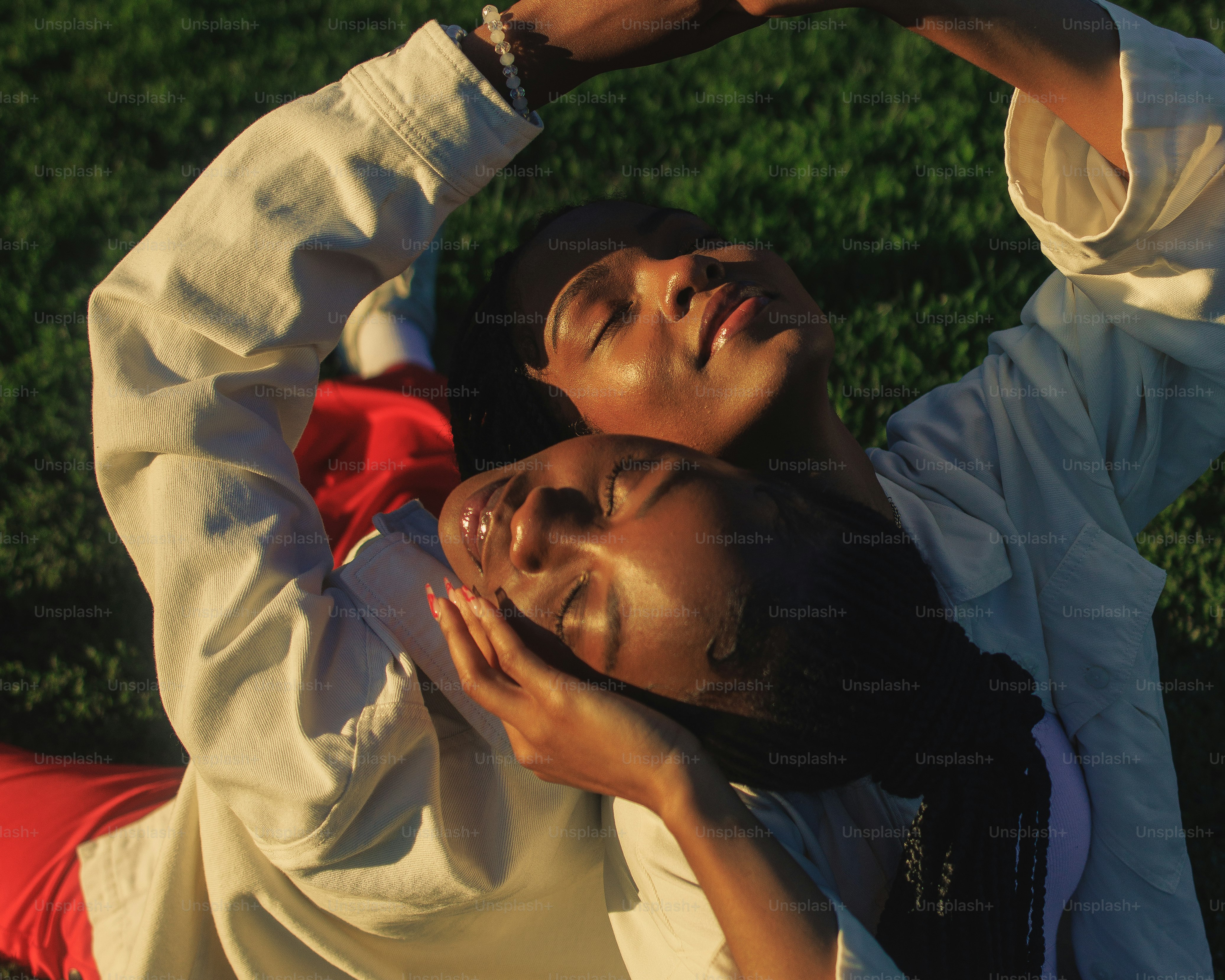 a couple of people laying on top of a lush green field