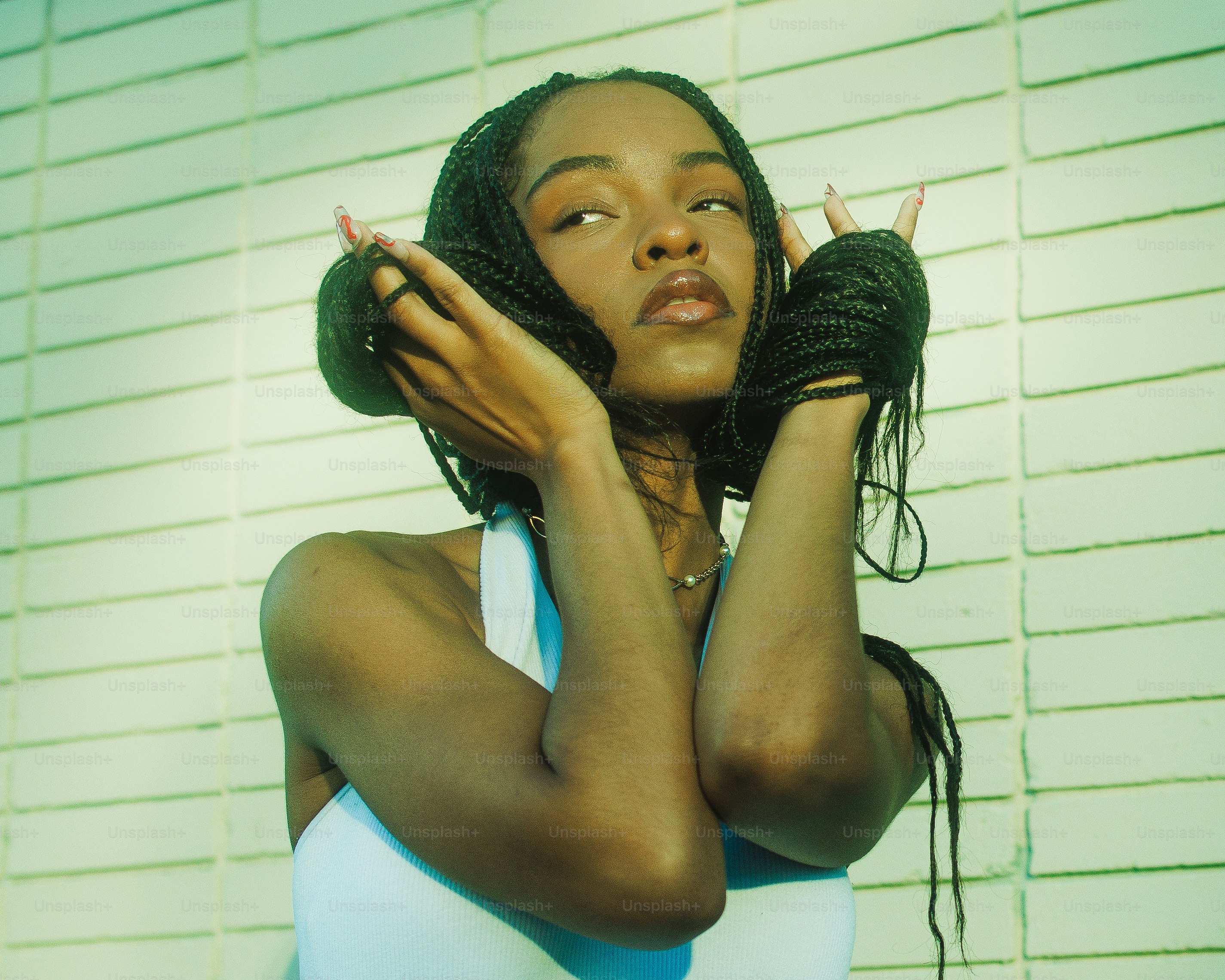 a woman with braids holding her hands to her ears