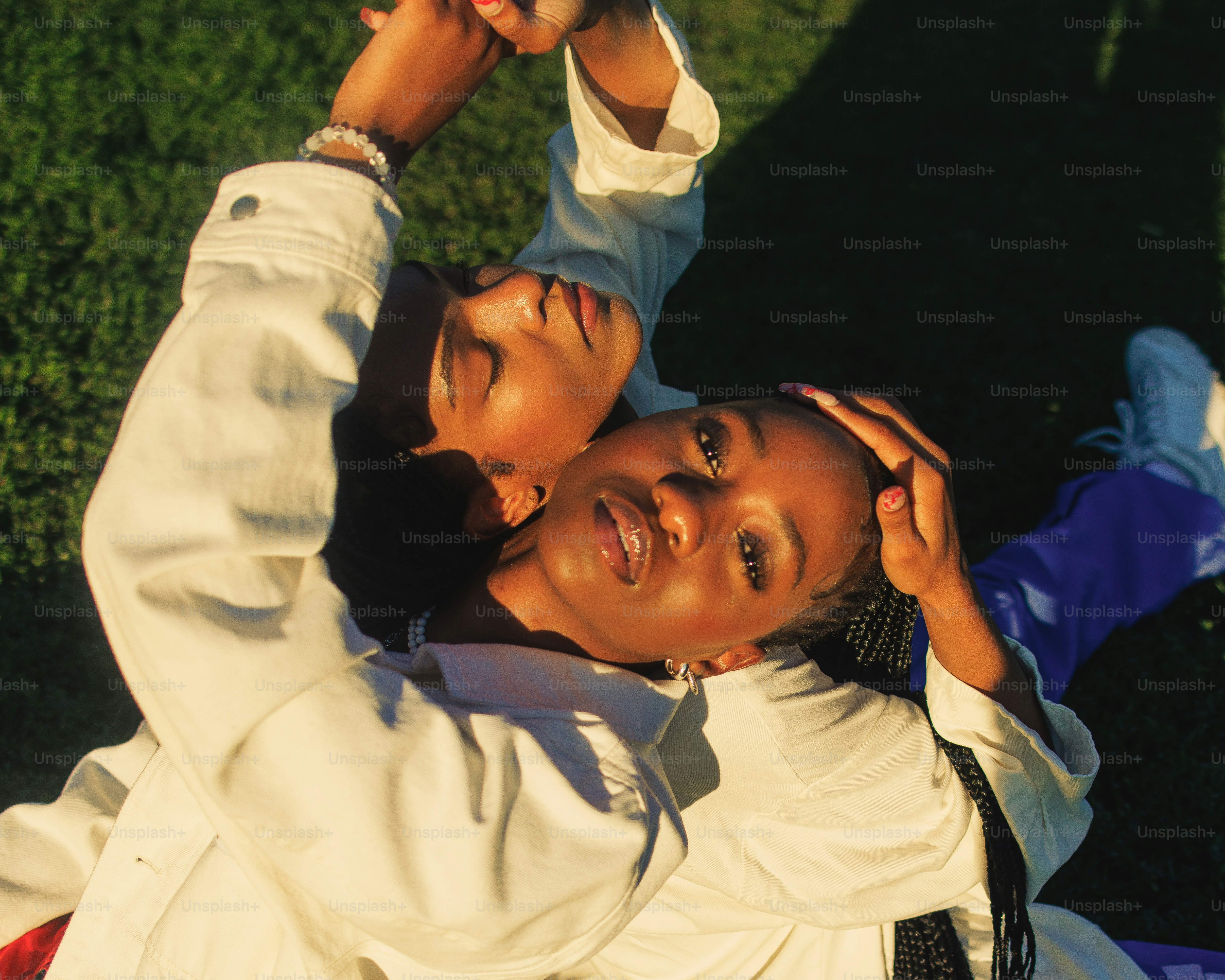 a couple of people laying on top of a lush green field