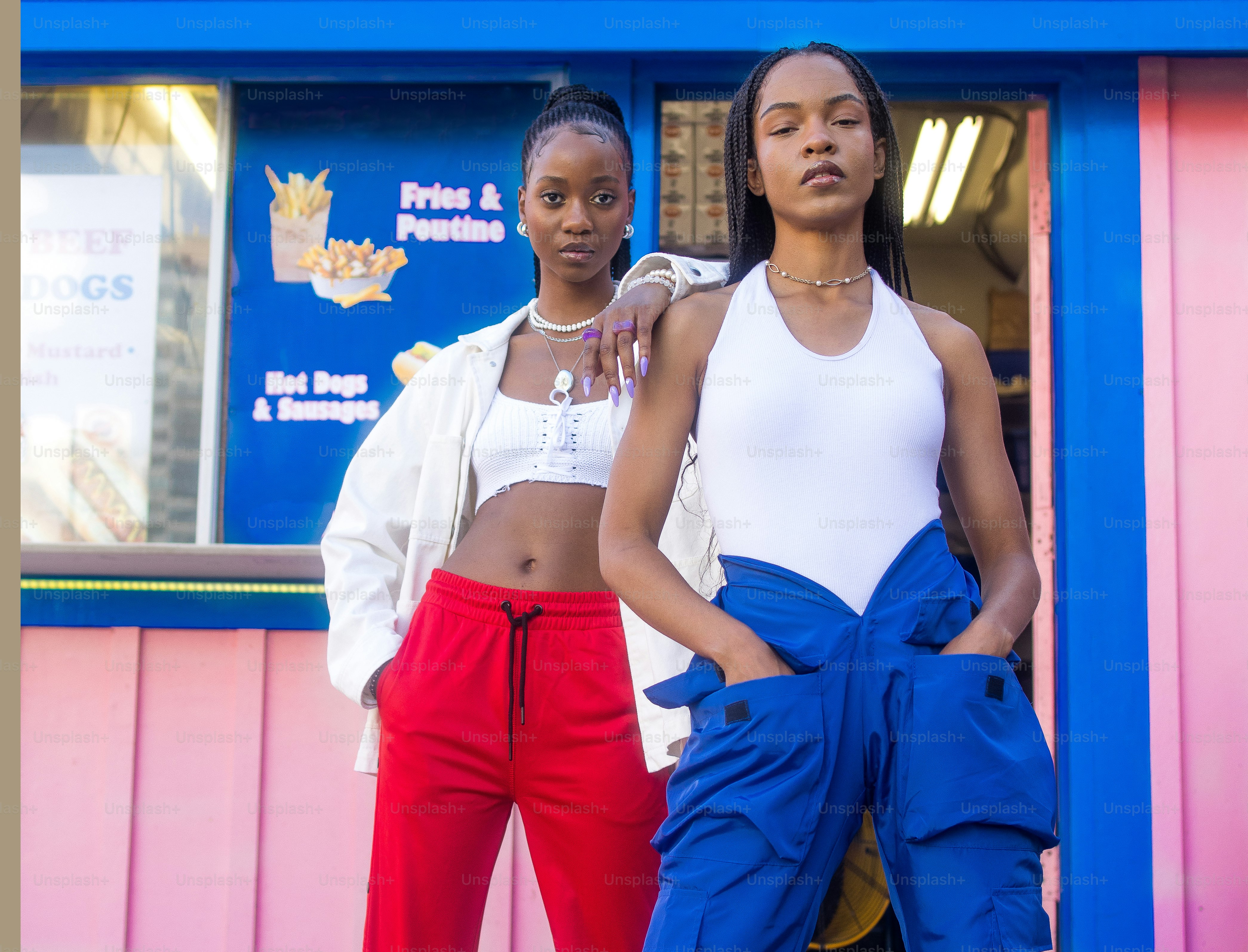 two women standing in front of a pink and blue building