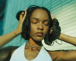 a woman wearing a white tank top holding her hair in her hands