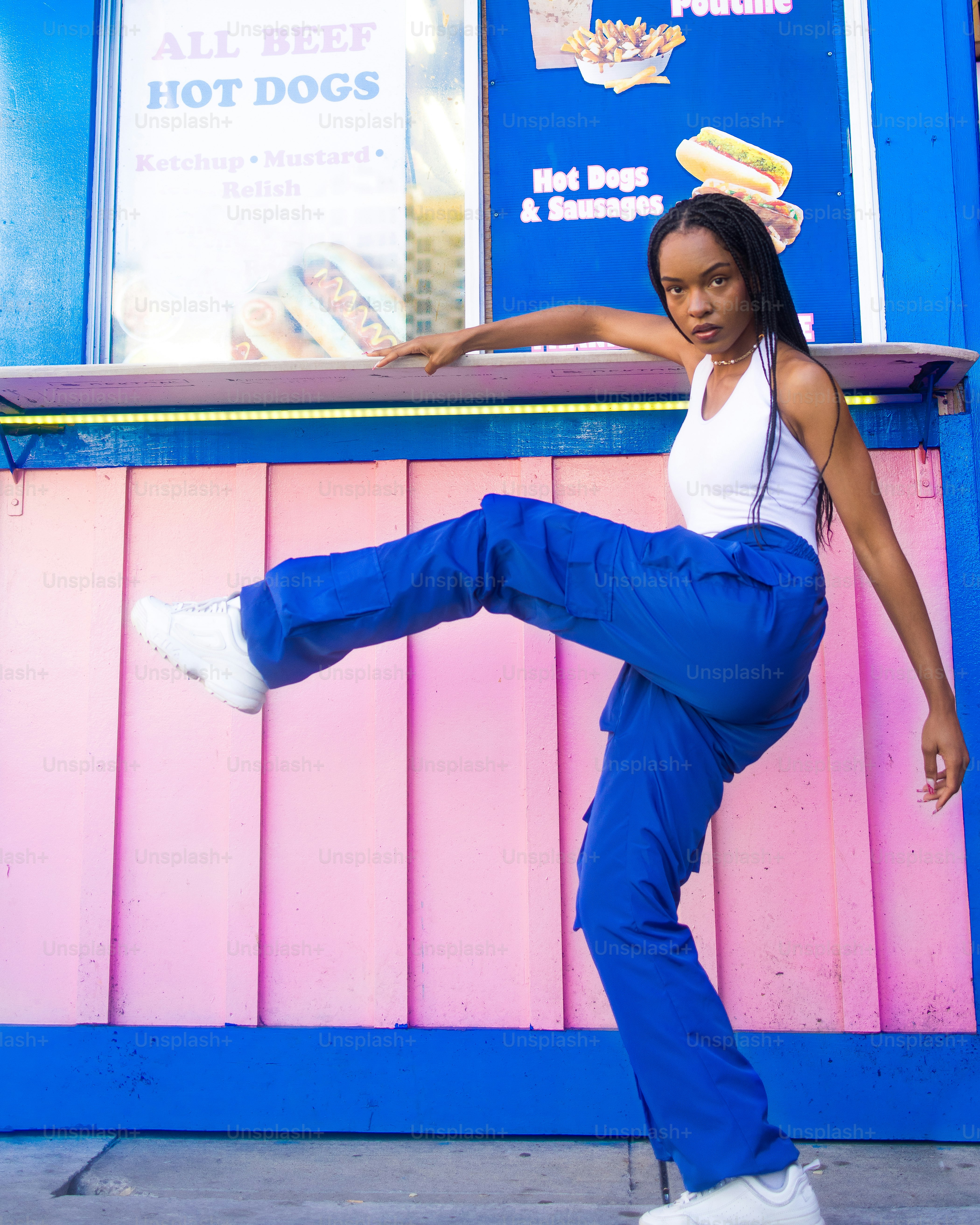 a woman doing a kick in front of a hot dog stand