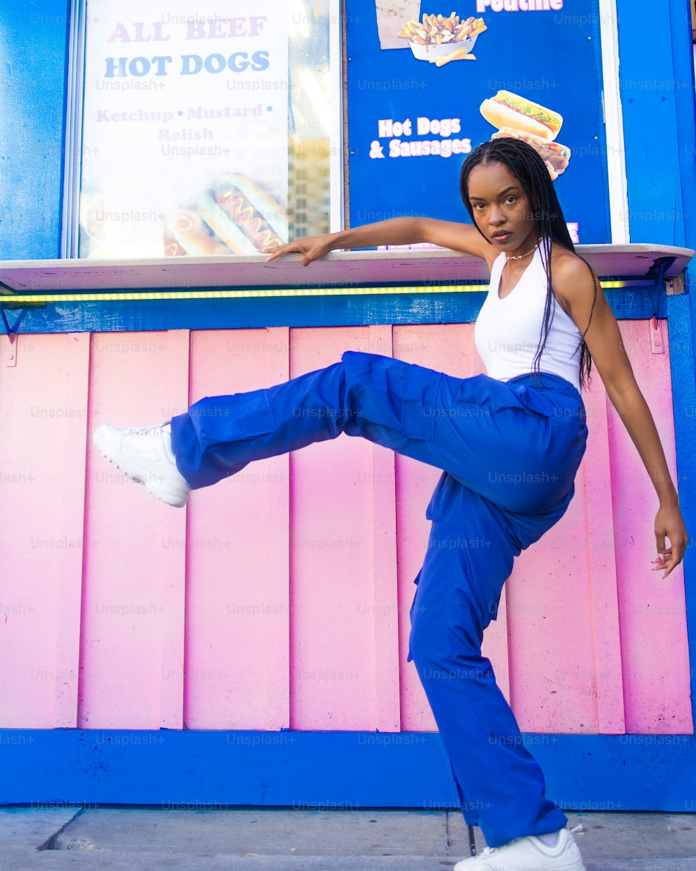 a woman doing a kick in front of a hot dog stand