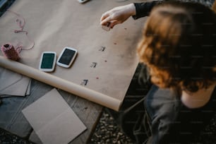 Una mujer sentada en una mesa con dos teléfonos celulares