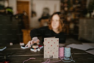 Eine Frau sitzt an einem Tisch mit einer Schachtel Garn