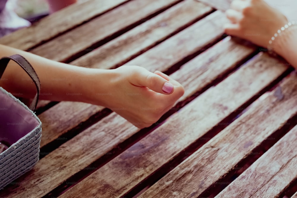 two people sitting at a wooden table holding hands
