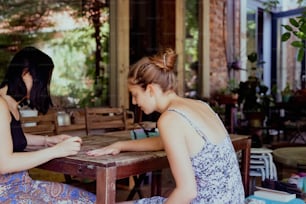 two women sitting at a table playing a game