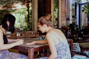 duas mulheres sentadas em uma mesa jogando um jogo