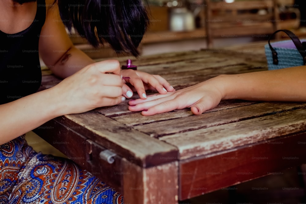 two women sitting at a table with their hands together