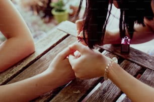 two women sitting at a wooden table holding hands