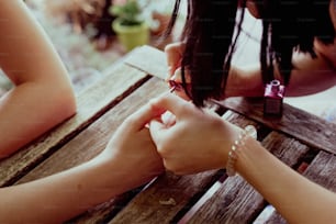 duas mulheres sentadas em uma mesa de madeira de mãos dadas