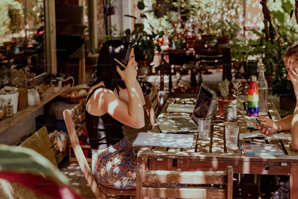 a couple of women sitting at a table with laptops