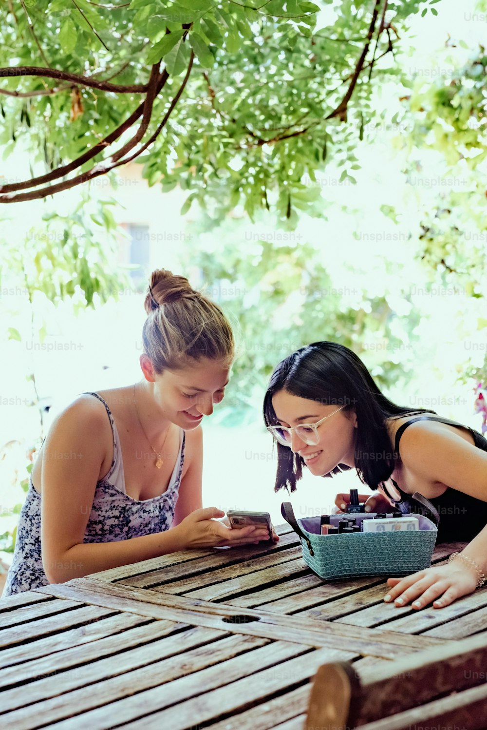 two women sitting at a table looking at a cell phone