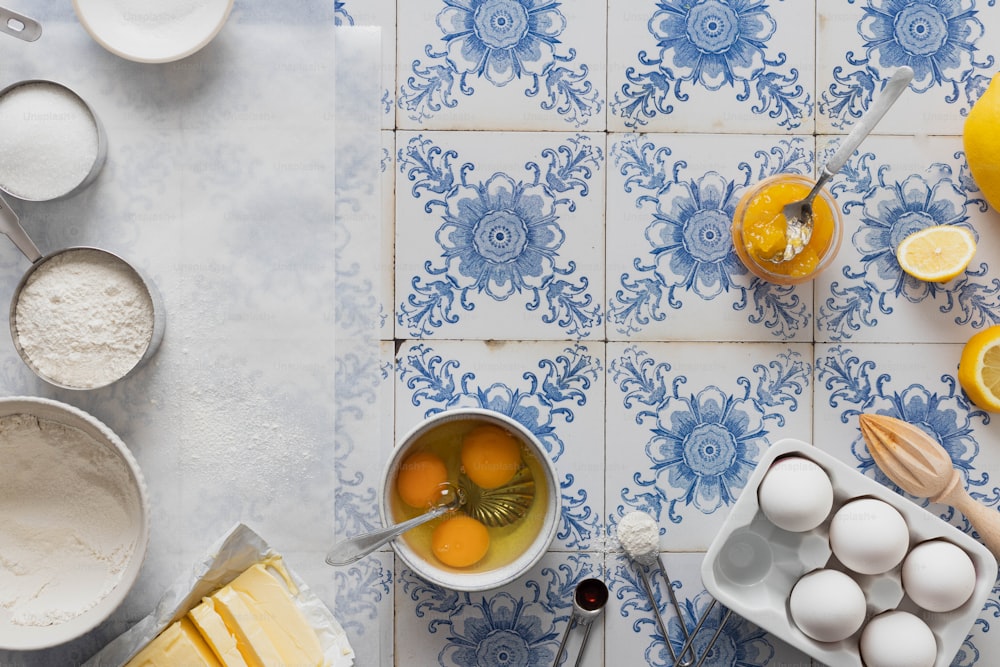 a blue and white tiled counter top with bowls of food and utensils