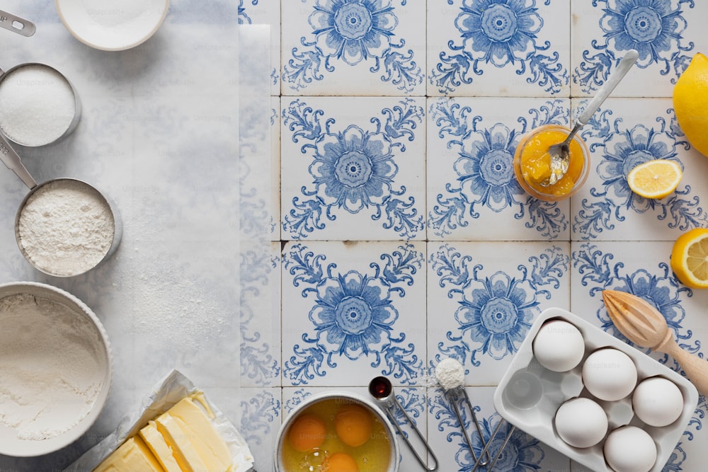 una encimera de azulejos azules y blancos con limones, huevos y otros ingredientes