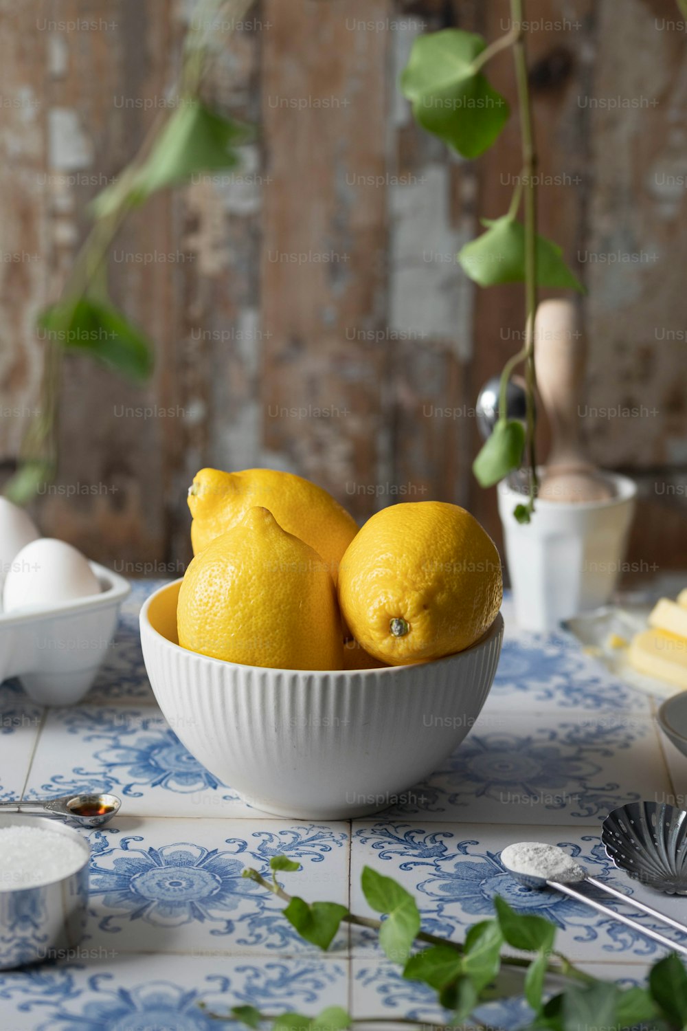 Un tazón blanco lleno de limones encima de una mesa