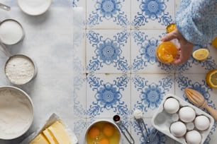 a person holding an orange in front of a blue and white tile wall