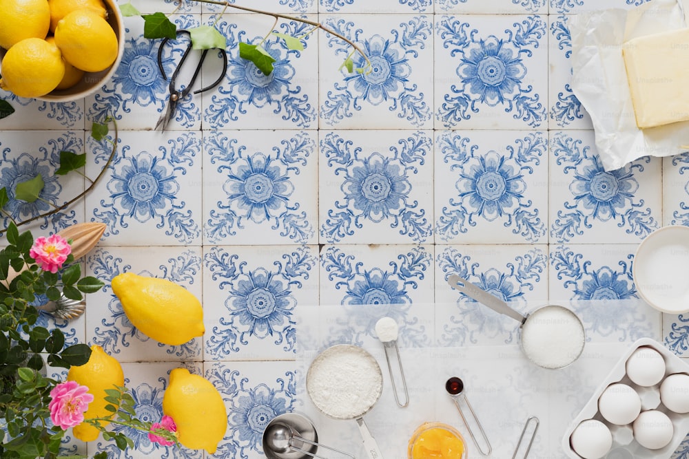 a blue and white tile with lemons, eggs, and utensils