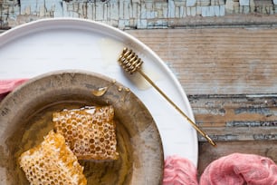 zwei Stücke Honig auf einem Teller neben einem rosa Wollknäuel