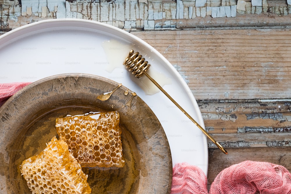 Deux morceaux de miel sur une assiette à côté d’une boule de laine rose