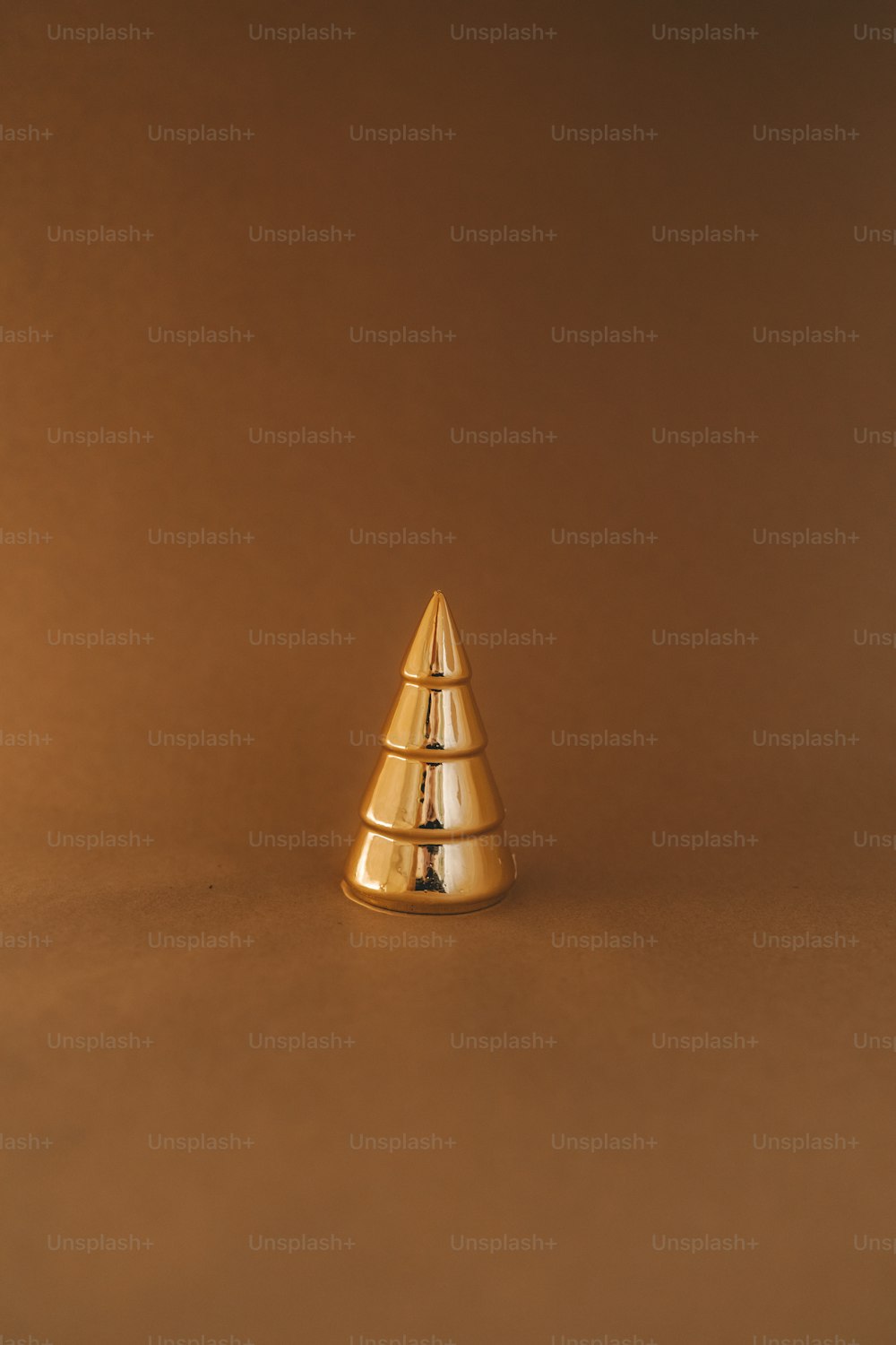 Un objeto en forma de cono de oro sobre un fondo marrón