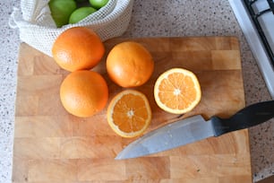 a cutting board topped with oranges and a knife