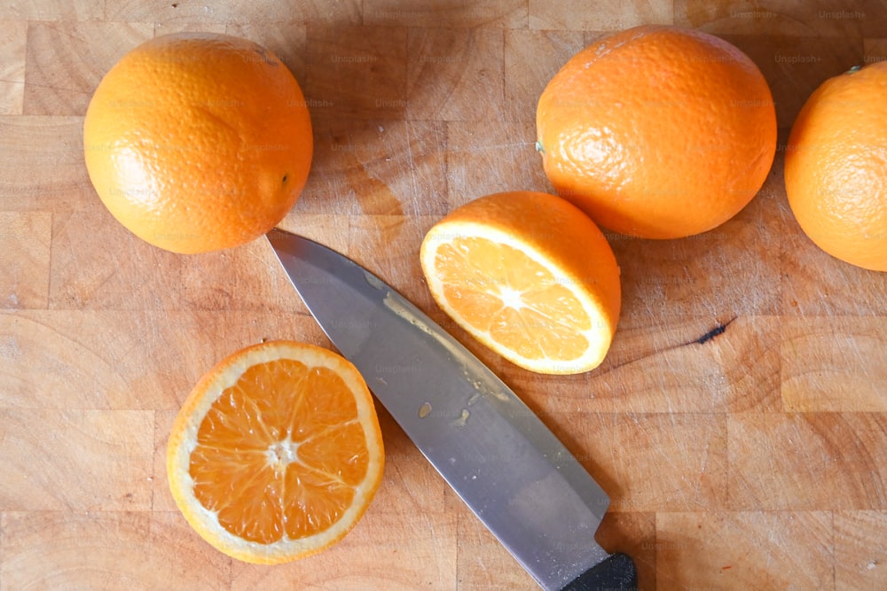 Tres naranjas y un cuchillo en una tabla de cortar