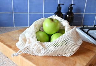 a bag of green apples sitting on top of a wooden cutting board