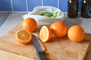 une planche à découper surmontée d’oranges et d’un couteau